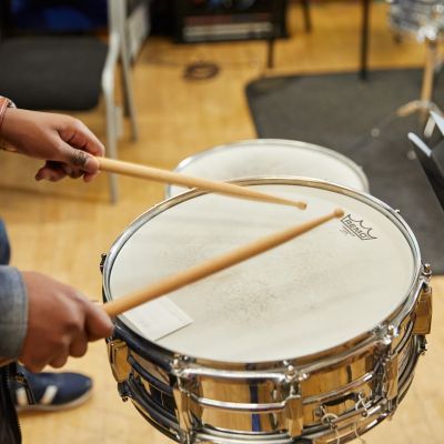 A close up image of some hands holding drum sticks over a drum kit.